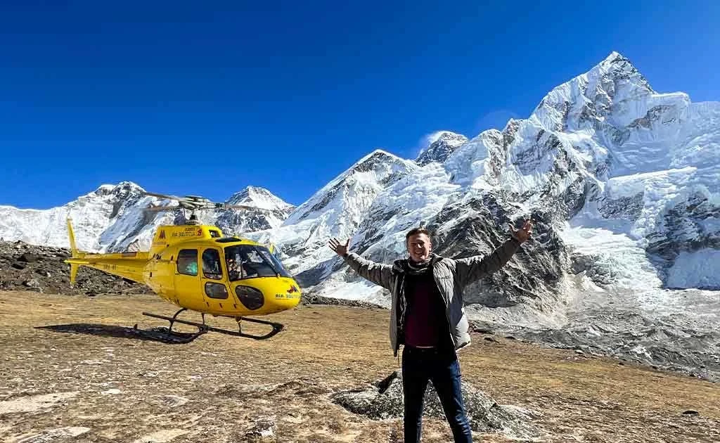 Traveler in layered winter clothing beside a helicopter at the Kala Patthar landing zone